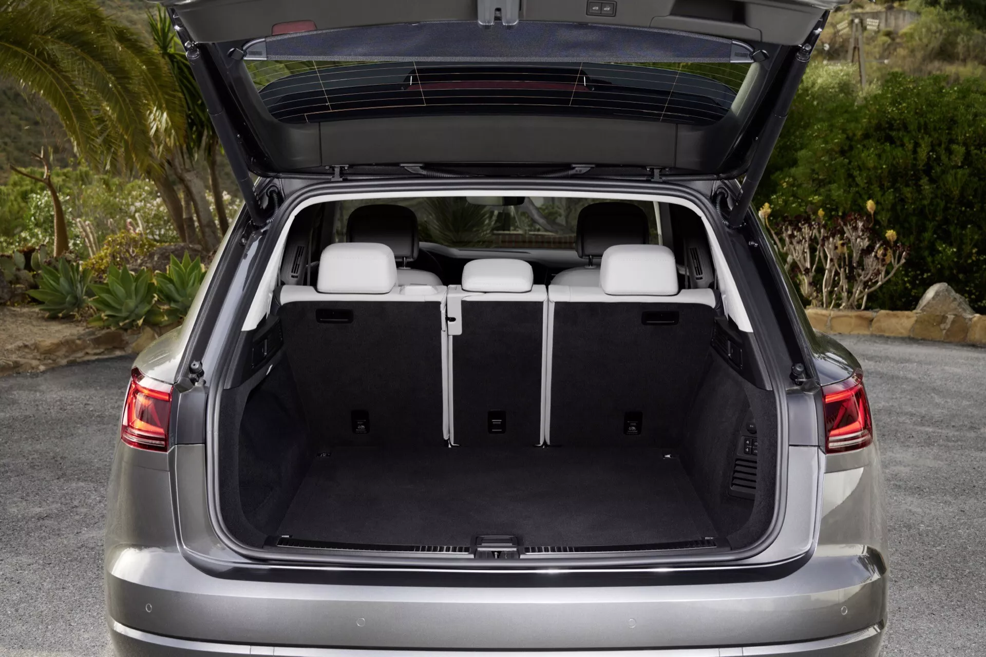 VW Touareg III-facelift 2023 révélé sous un angle arrière avec le coffre ouvert montrant un espace de chargement spacieux, un plancher de chargement plat et une couverture de chargement rétractée, soulignant le design moderne du SUV et les fonctionnalités de sécurité avancées
