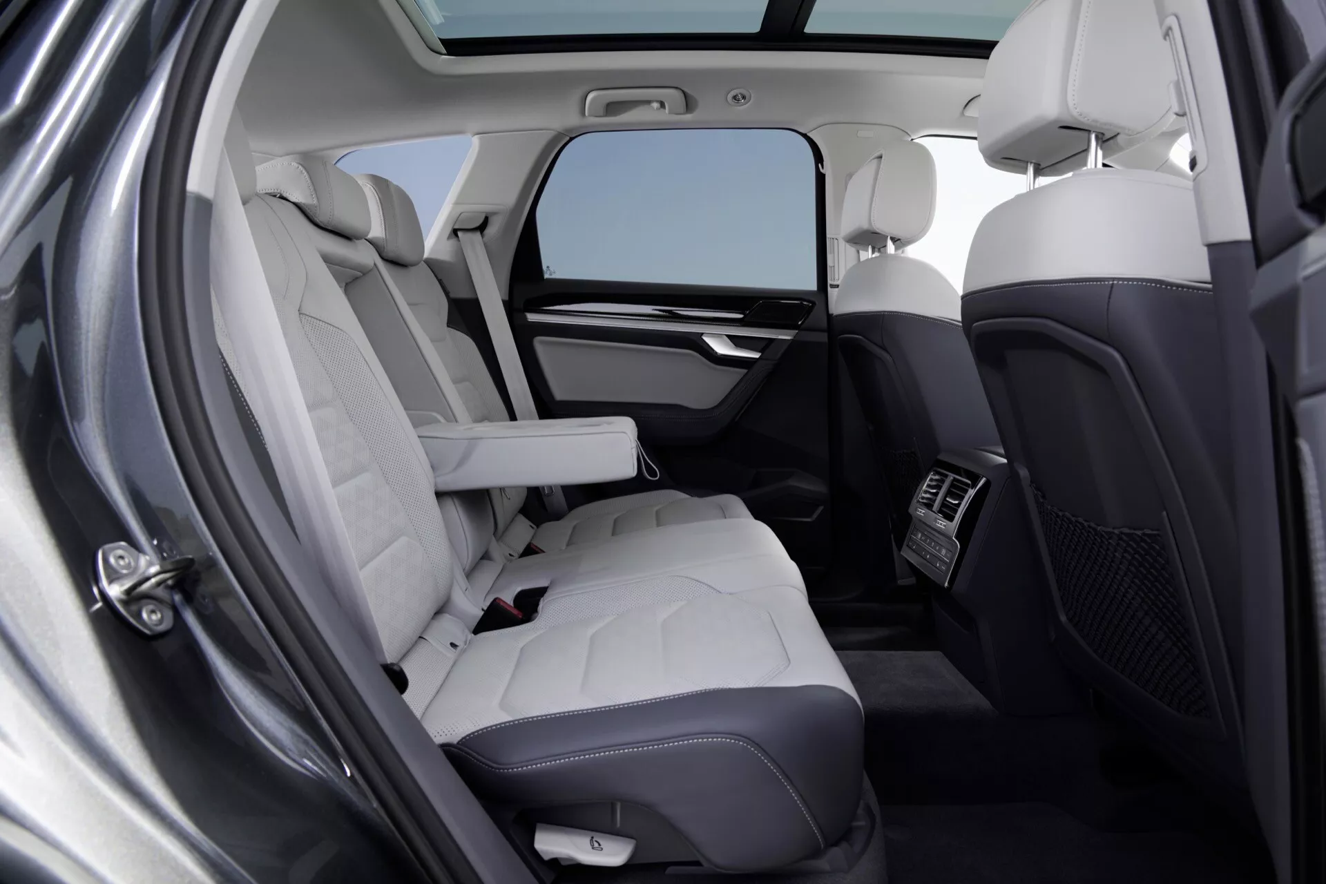 Intérieur du VW Touareg 2023 (III Facelift) présentant des sièges arrière luxueux avec des sièges en cuir matelassé de couleur claire, des fonctionnalités technologiques intégrées et un éclairage par toit panoramique