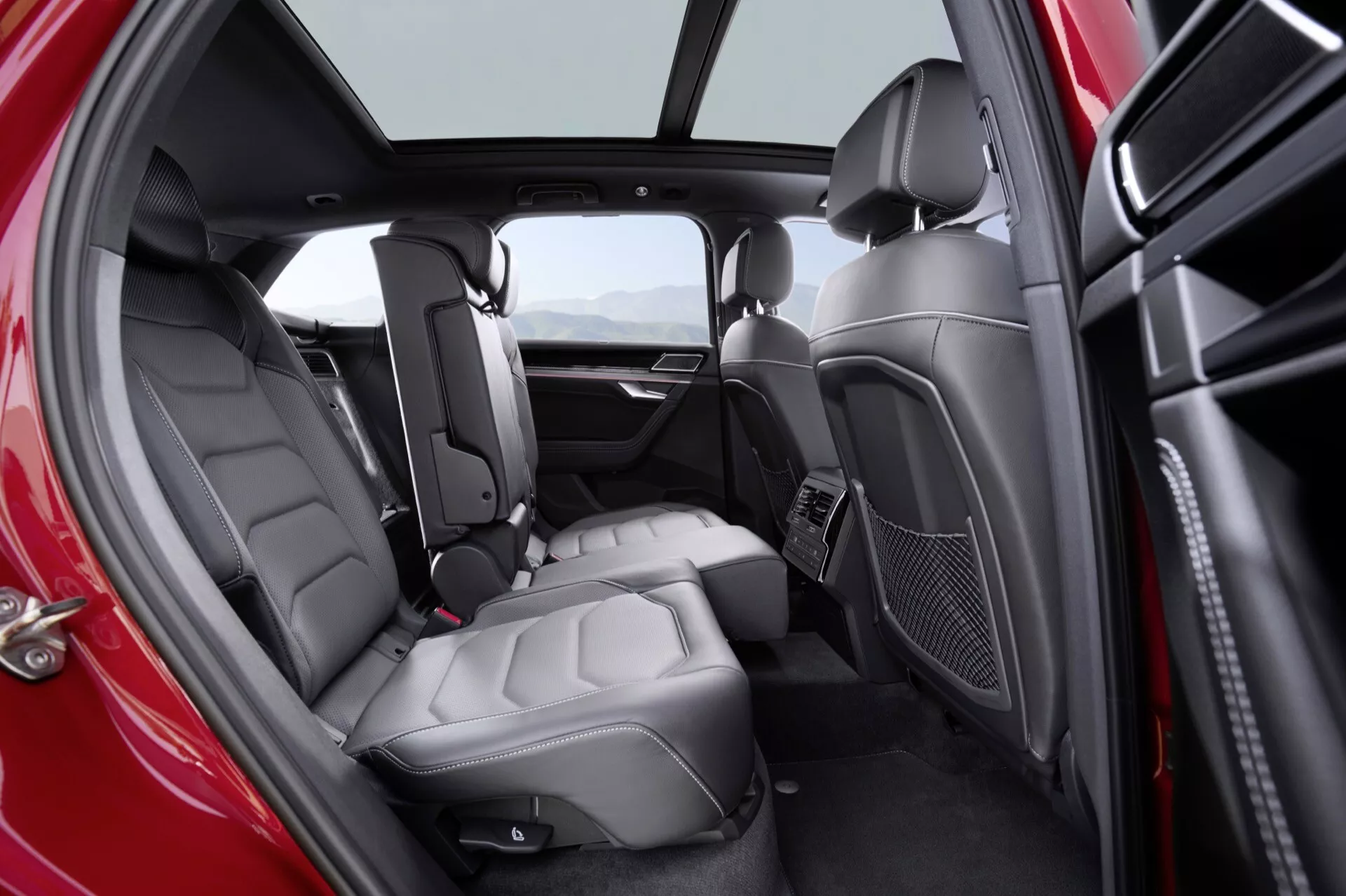 Intérieur du Volkswagen Touareg III Facelift 2023 montrant le siège arrière haut de gamme à travers la porte ouverte côté conducteur, mettant en évidence la sellerie en cuir de qualité, les fonctionnalités technologiques avancées et les éléments de design de luxe