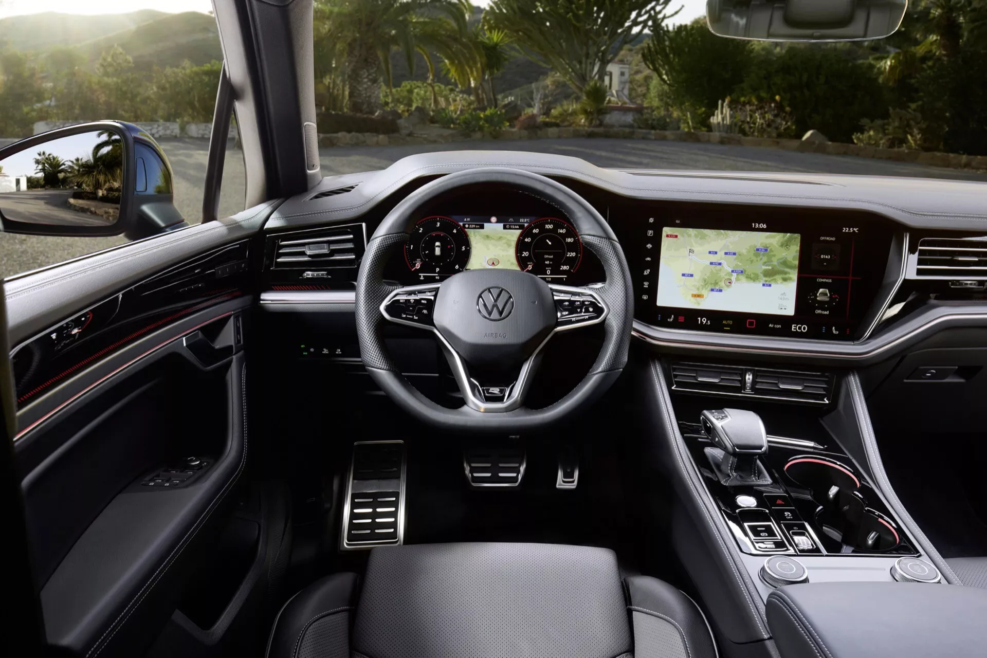 Vue intérieure du VW Touareg 2023 mettant en avant le volant multifonctions en cuir avec logo Volkswagen, tableau de bord numérique, système d'infodivertissement tactile et sélecteur de vitesse élégant dans un cadre de luxe aux tons sombres et accents métalliques