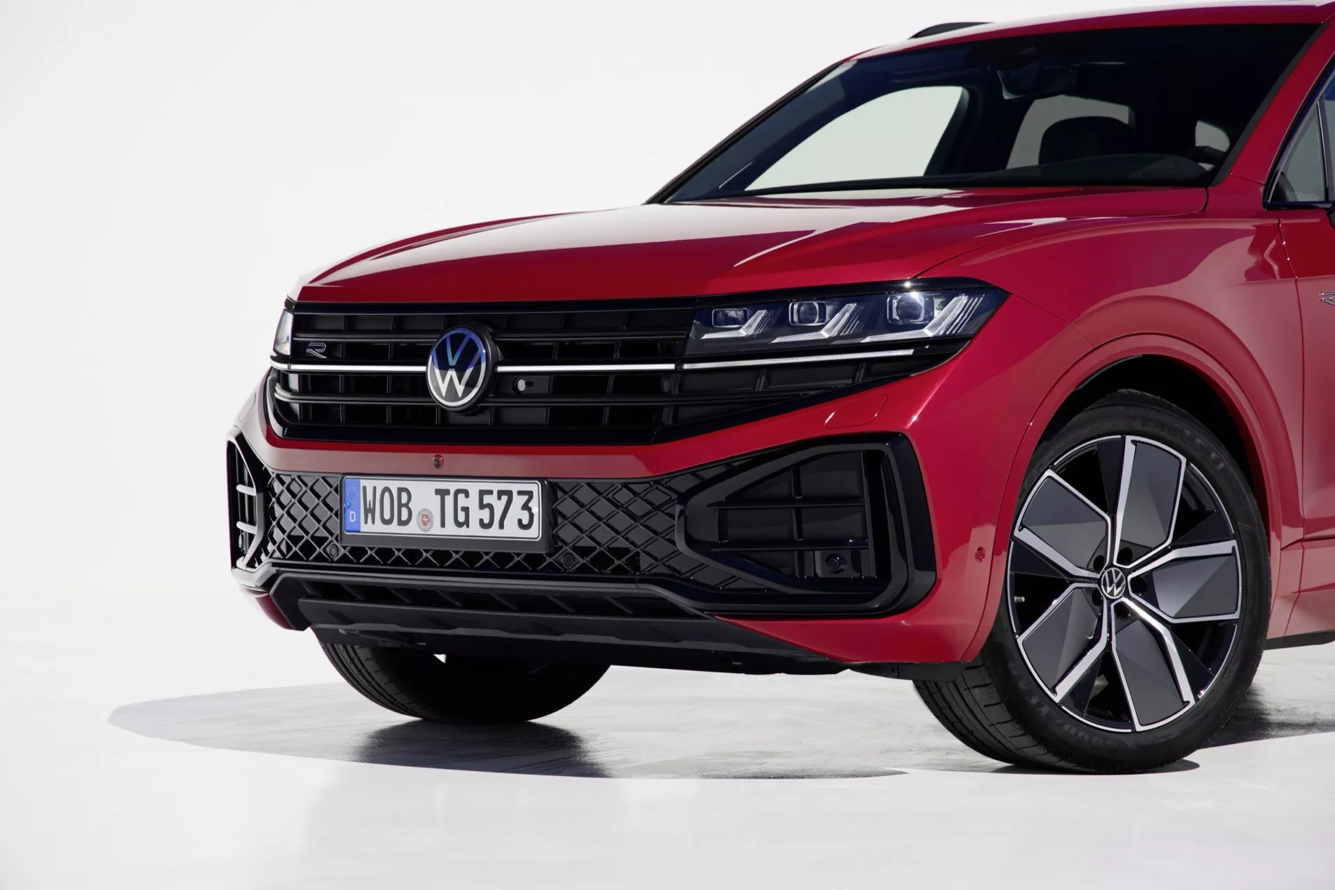 Vue de face gauche du Volkswagen Touareg 2023 mettant en évidence ses phares LED, sa grille sportive et sa finition rouge orientée performance