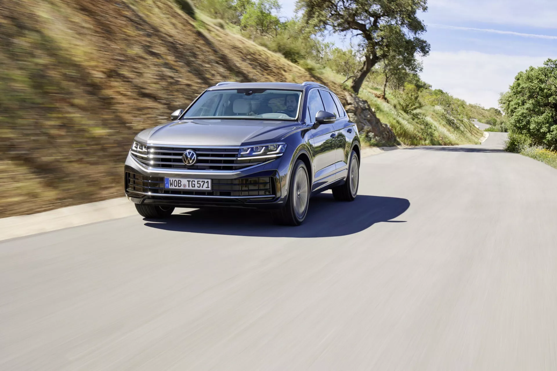 VW Touareg III facelift 2023 présenté dans un cadre routier dynamique, mettant en avant les phares LED, la grille moderne, les roues en alliage sportives et les fonctionnalités ADAS.